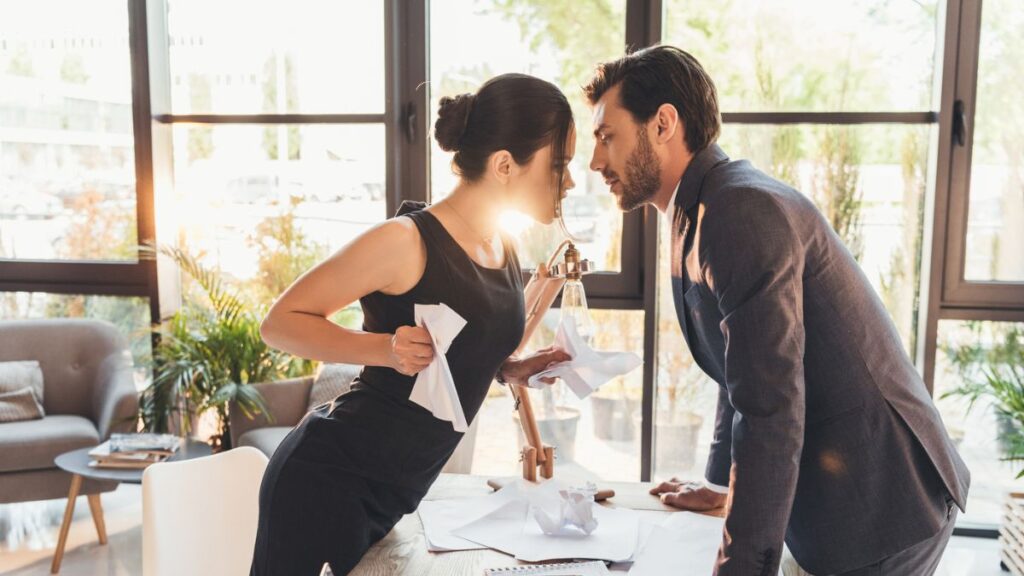 woman and man in dressy black clothes arguing over a table