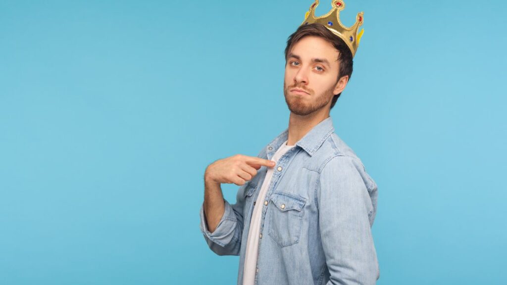 Arrogant man standing pointing to himself with a crown looking arrogant.