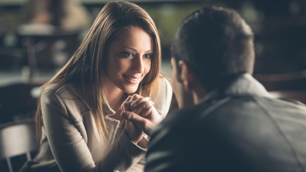 Attraction couple holding hands at a table looking happy and flirty