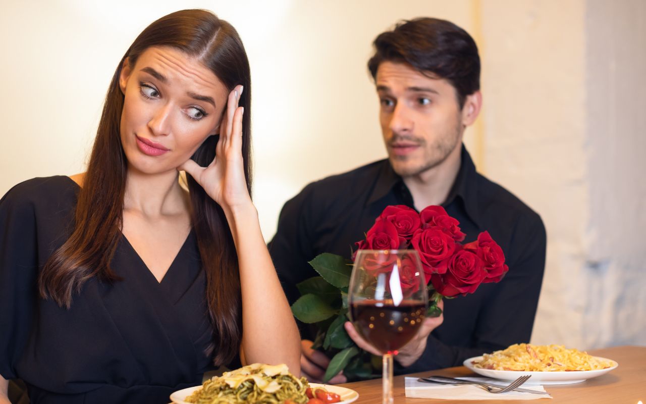 Bad date woman looking awkward covering her expression man at a table