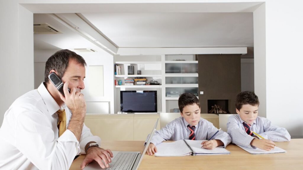 Being Around Kids: man on the phone sitting at a table with two boys, books and his laptop