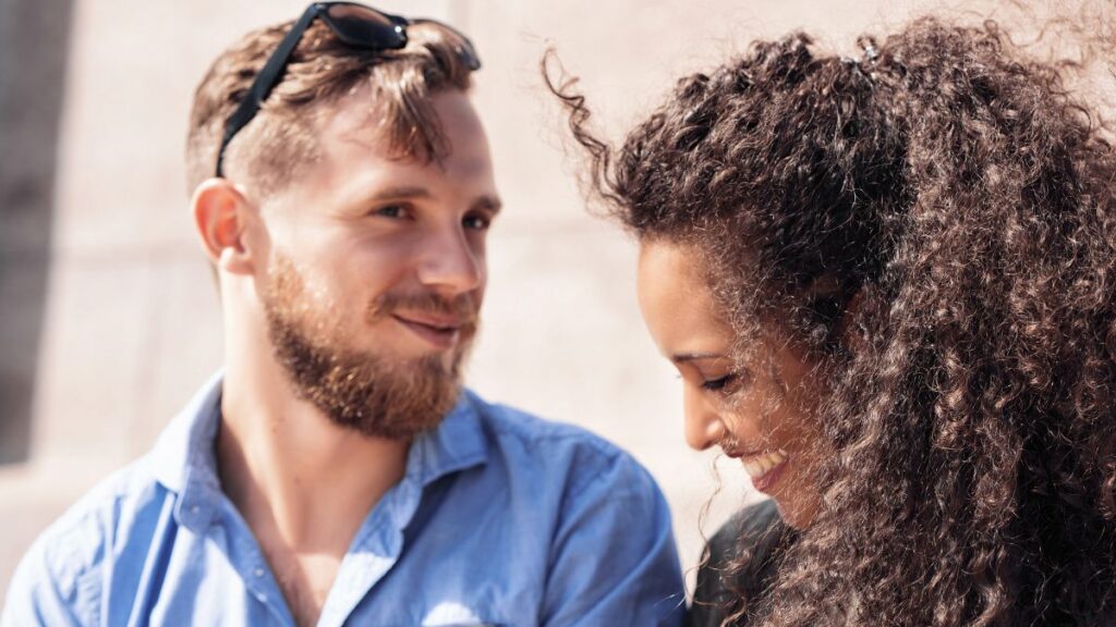 Being Shy/Timid: man sitting with man smiling and looking shy.