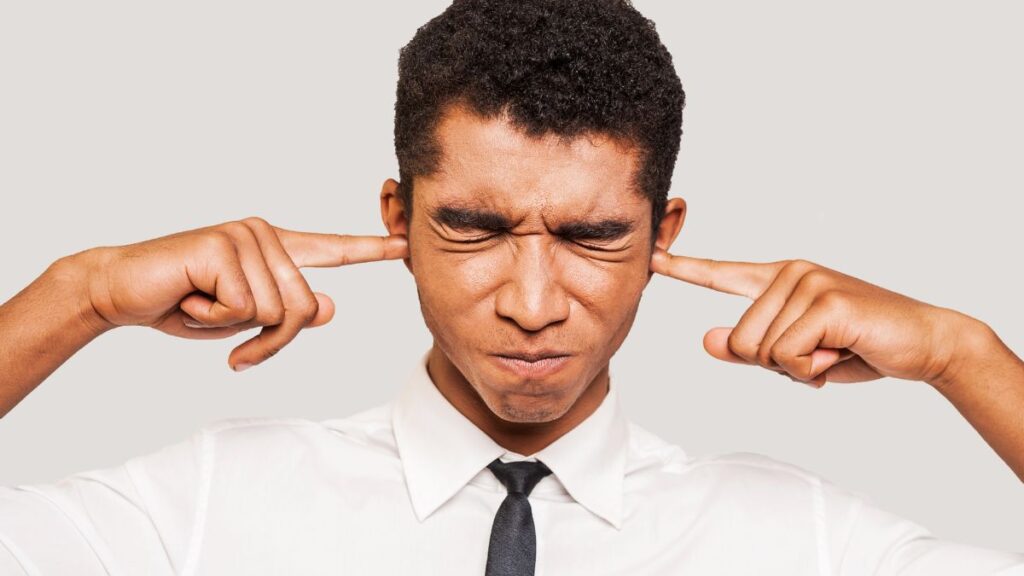 Bully: man standing with his eyes tight shut and fingers in his ears.