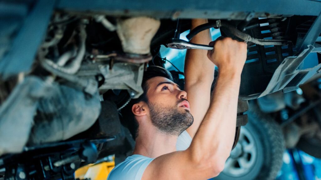 Car Work man under car in garage working on it