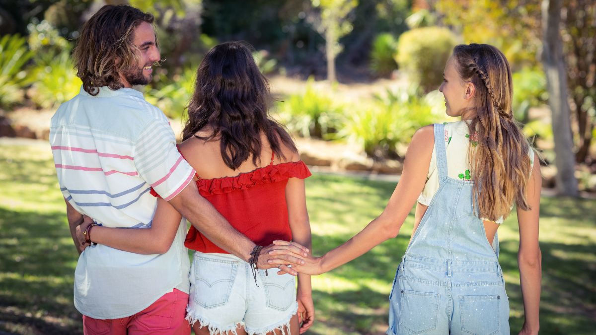 cheaters holding hands behind girls back