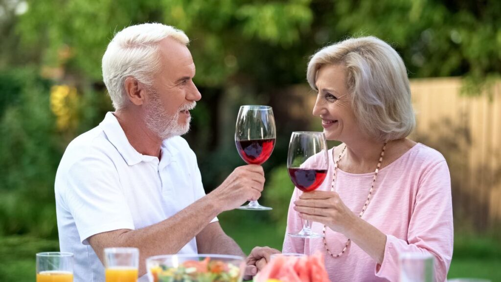 Compliment Them man and woman doing cheers with wine outside at a table