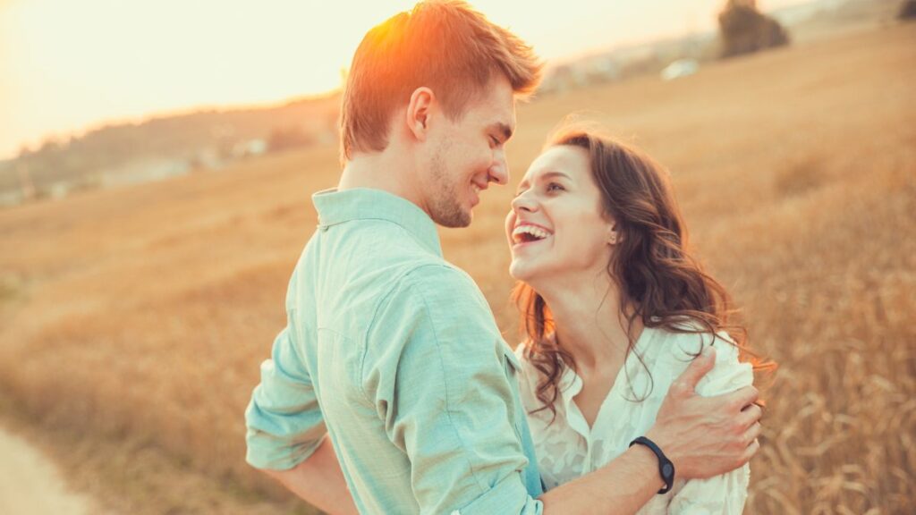 couple hugging and smiling in a field