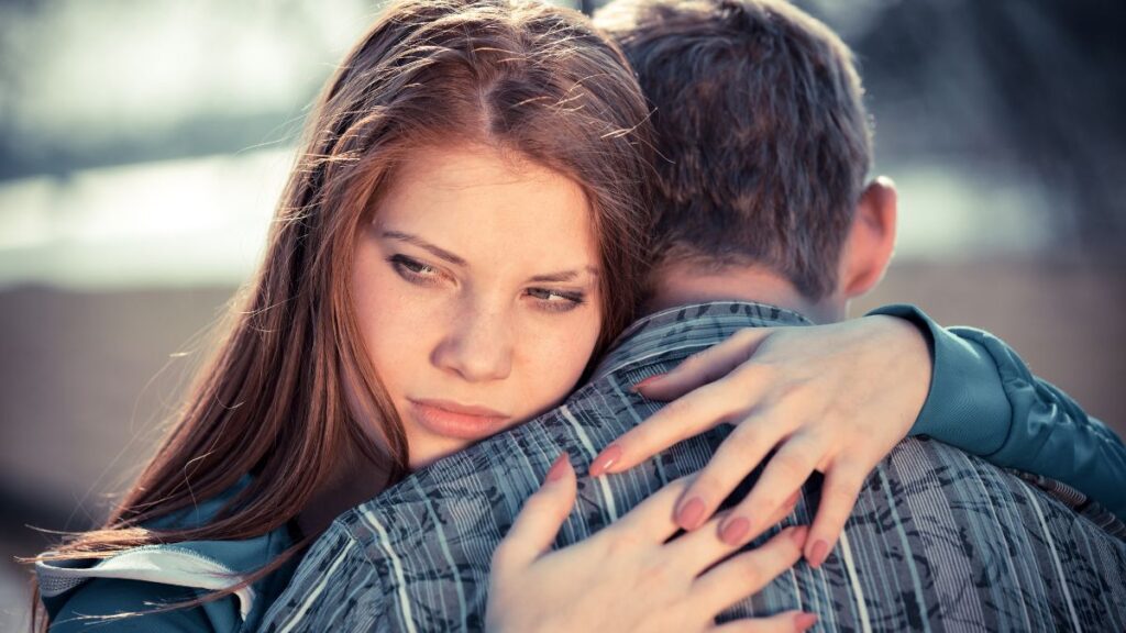 couple hugging woman looking upset