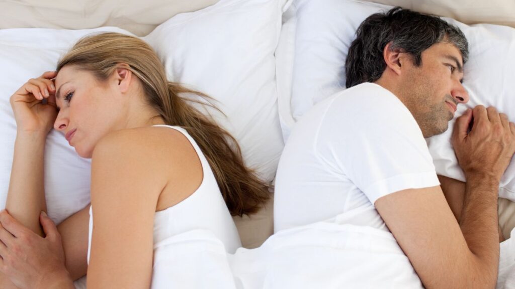 couple laying back to back looking upset