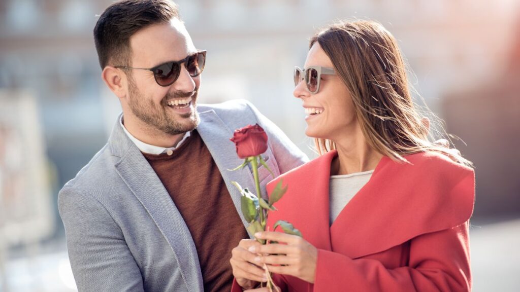 couple standing together holding a rose