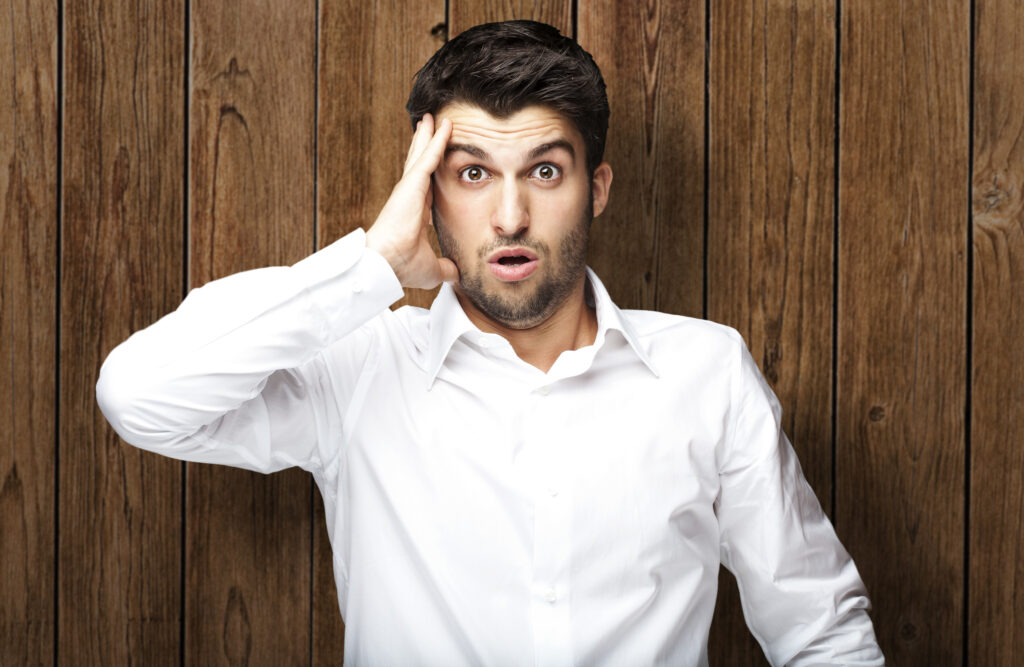 portrait of young man surprised against a wooden wall