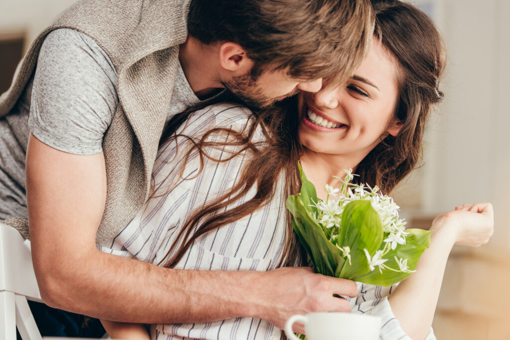 woman and man cuddling with flowers