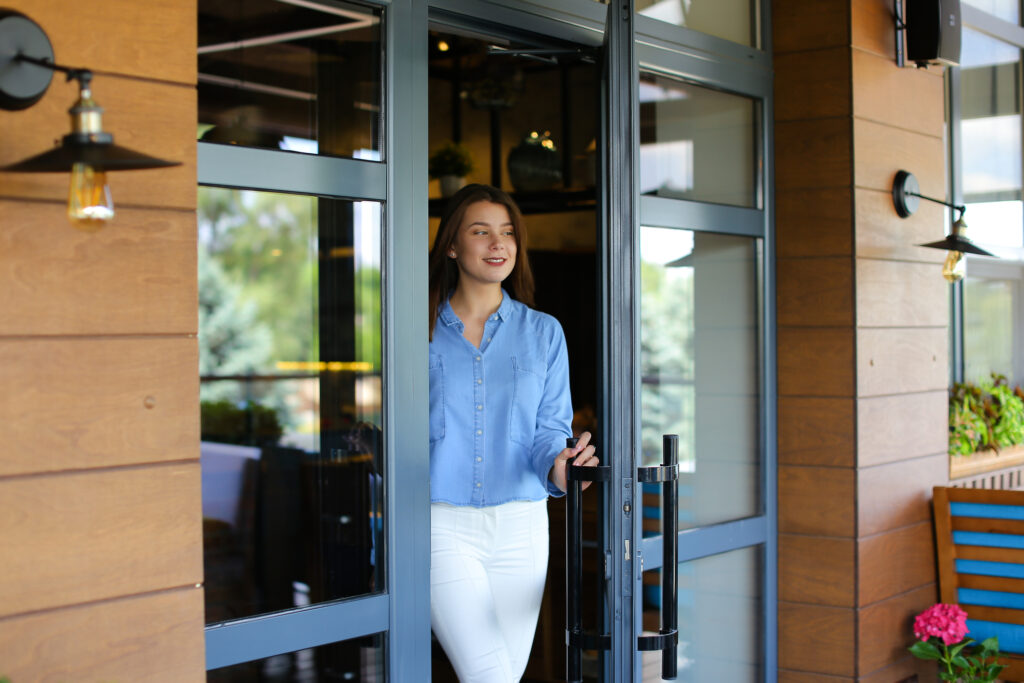 Cheerful woman leaving restaurant, talking by smartphone and loo