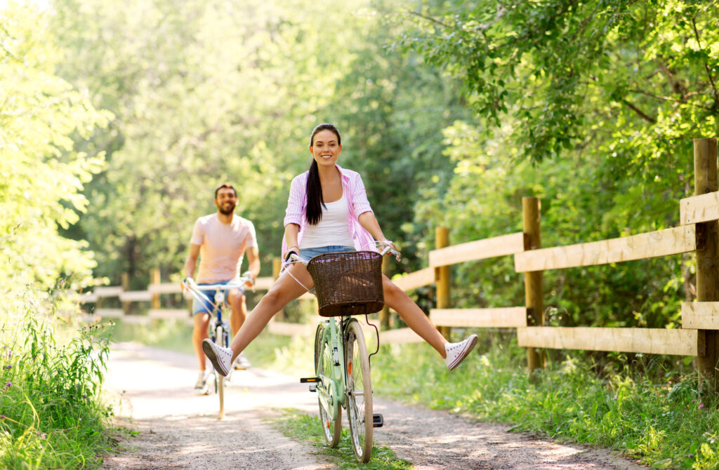 cycling, leisure and lifestyle concept - happy young couple with bicycles at summer park