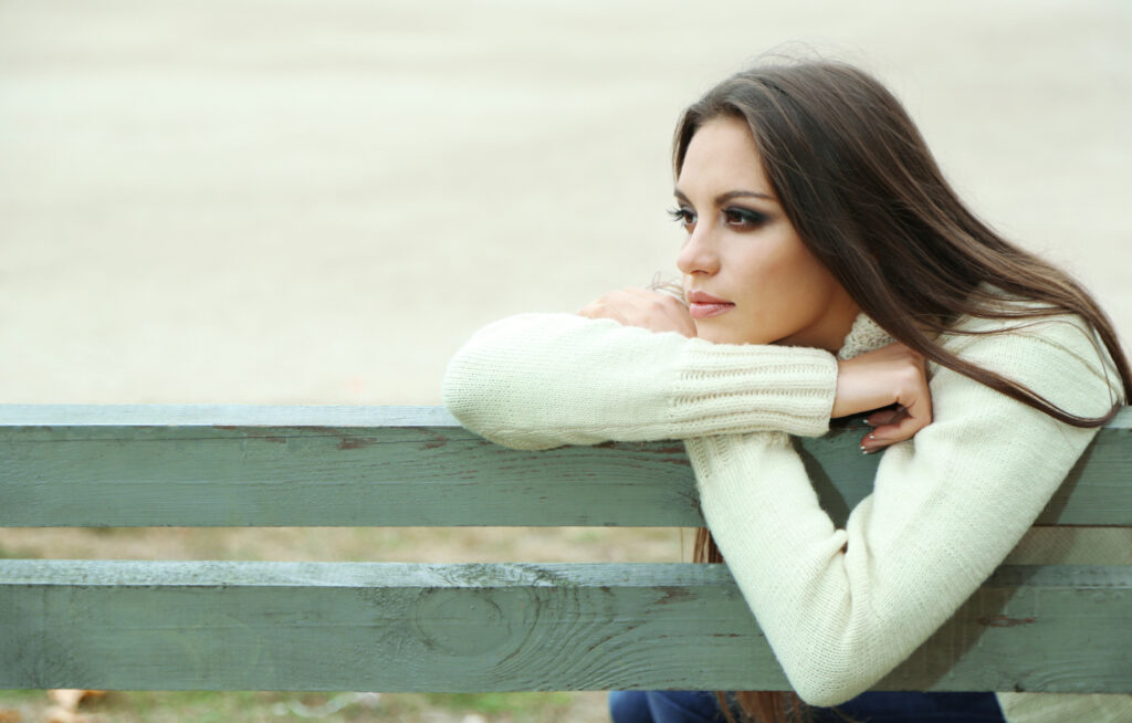 Young lonely woman on bench in park