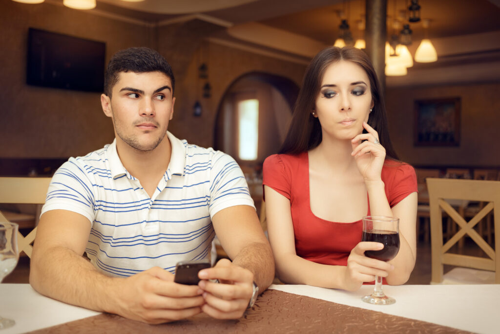 woman looking over her fiance's shoulder to his phone