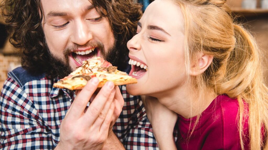 Dollar Pizza man and woman eating a slice of pizza