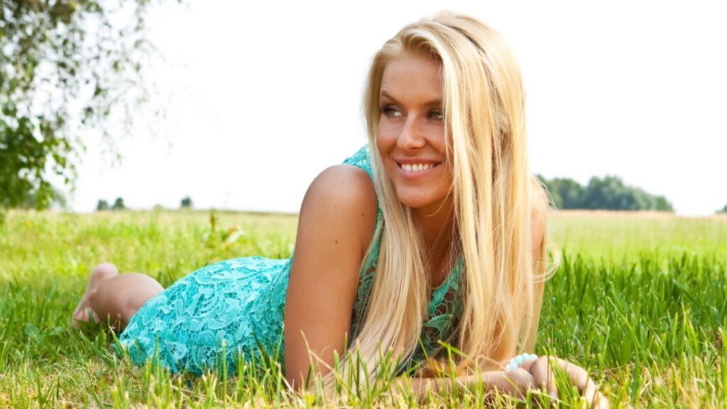 Down To Earth woman laying in the grass smiling