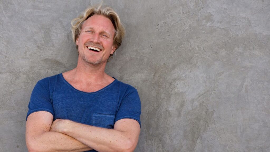 happy man smiling with arms crossed in a blue shirt