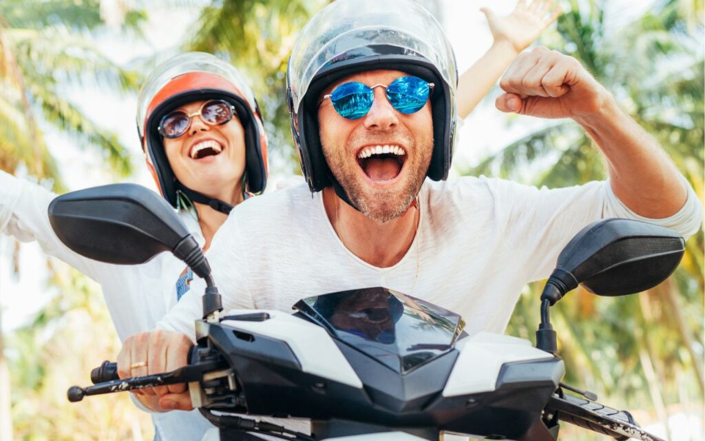 Happy smiling couple travelers riding motorbike scooter