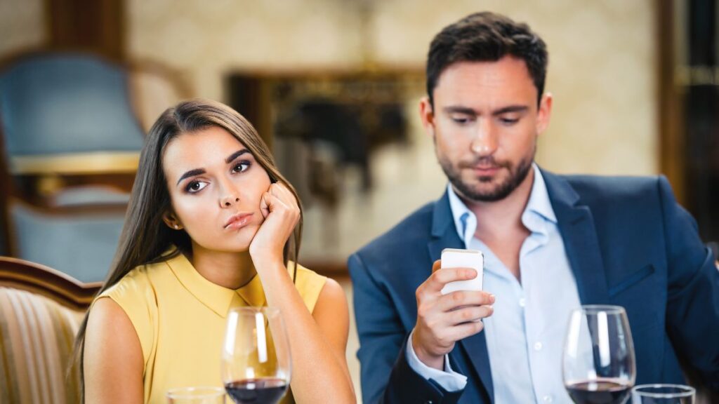 man and woman sitting at a dinner table looking bored