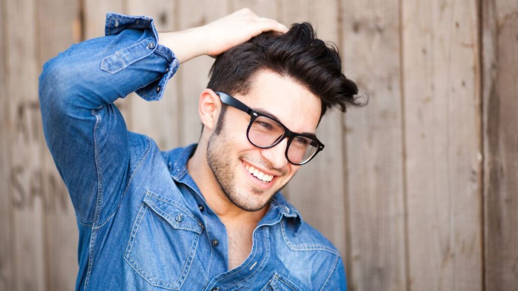 Keeping Up With Fashion: Man smiling in a denim shirt and black glasses.