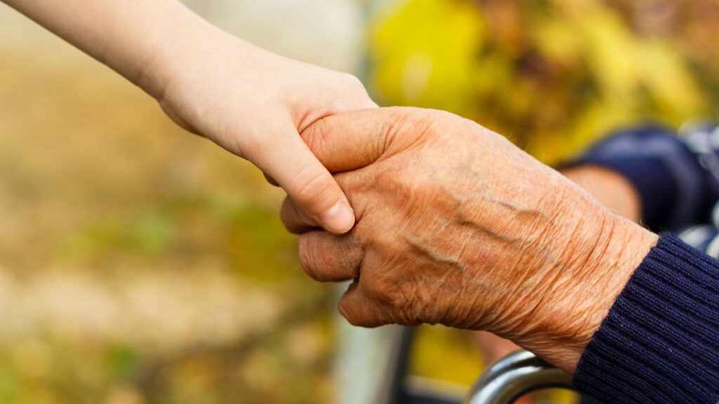 Kindness older and younger hands clasped together