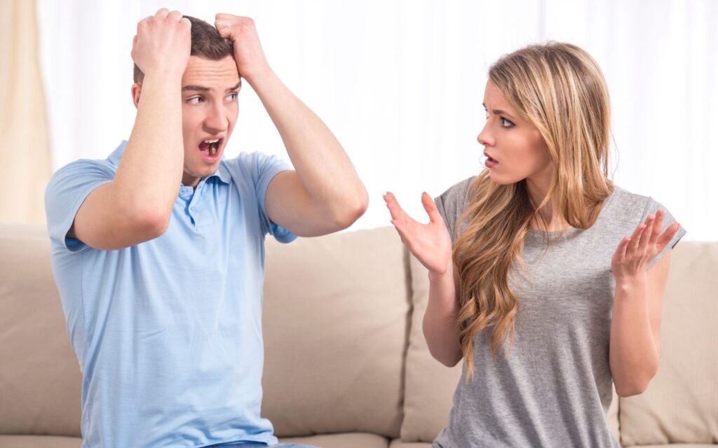 man and woman arguing on the couch