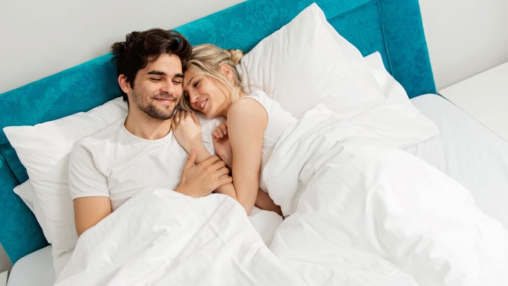 man and woman cuddling in bed 