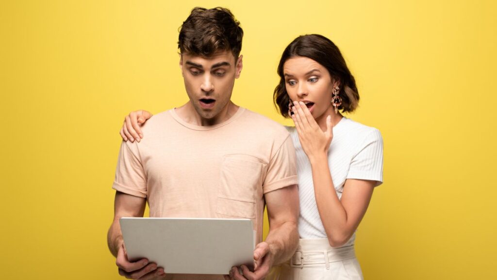 Man and woman looking at their computer shocked