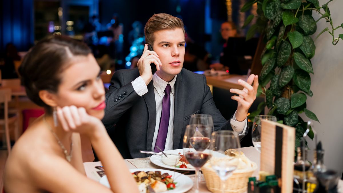 Man and woman on a date while man is on the phone