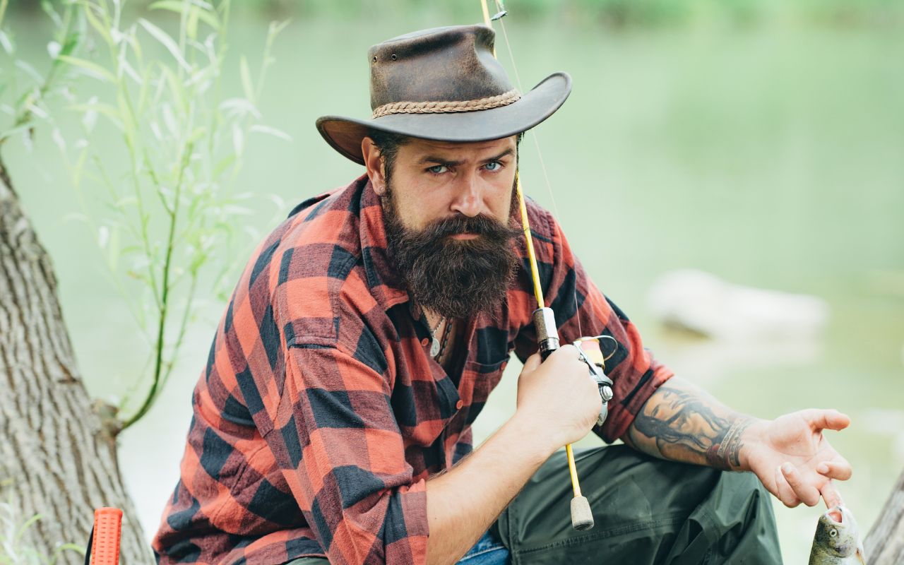 Man dressed for fishing sitting on a tree log