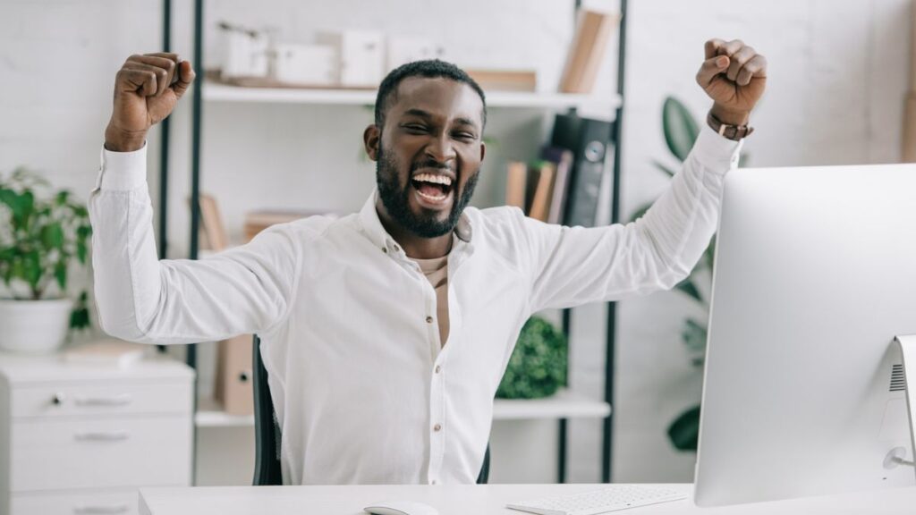 African american business man Happy at his desk with his arms in the air