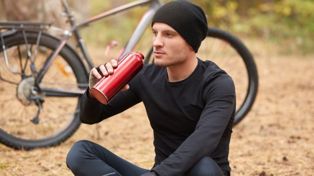 Man in a track suit, drinking water by his bike