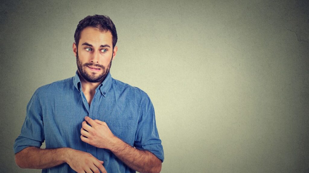 man looking awkward holding his shirt