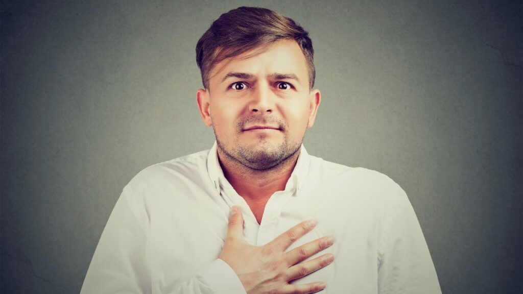 man looking concerned with hand on heart