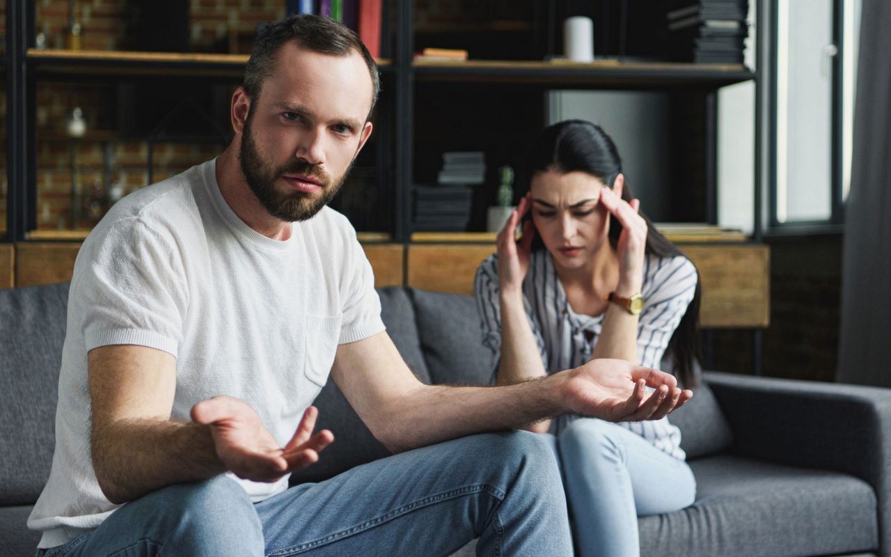 Man looking confused, woman is upset, both are sitting on the couch