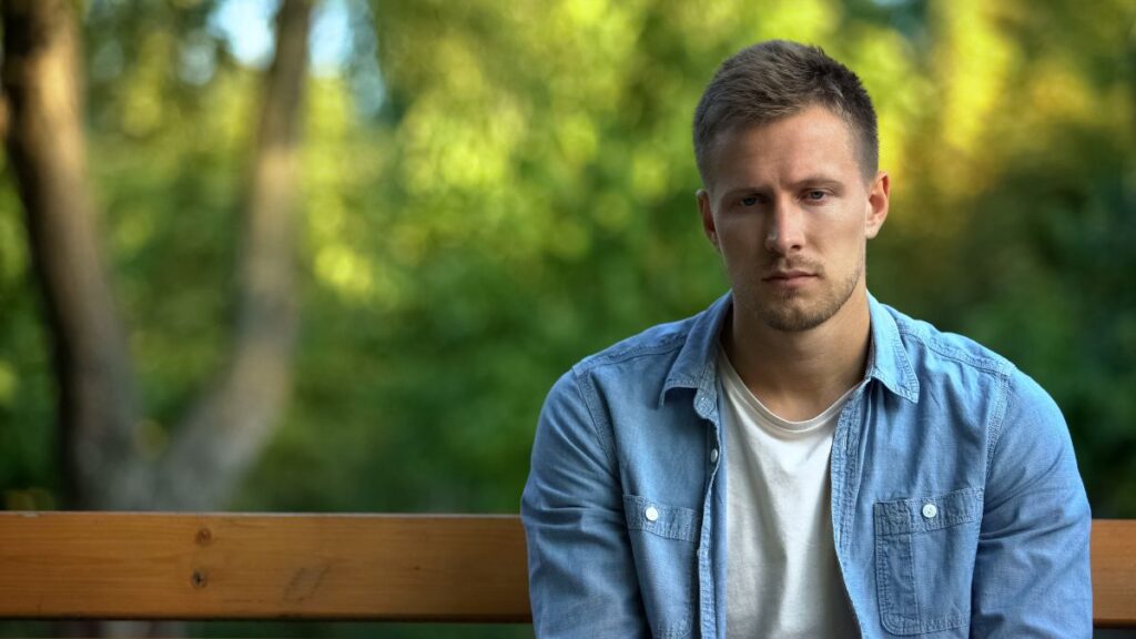 man looking sad sitting on a bench