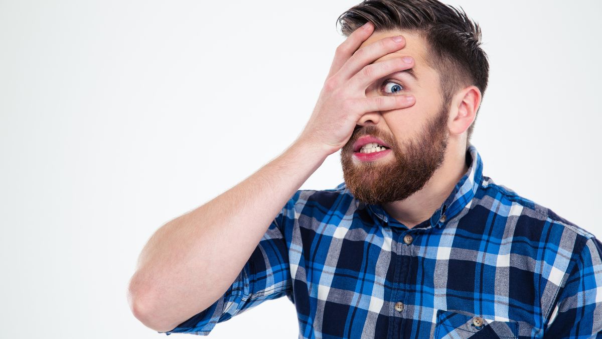 Man looking scared through his fingers