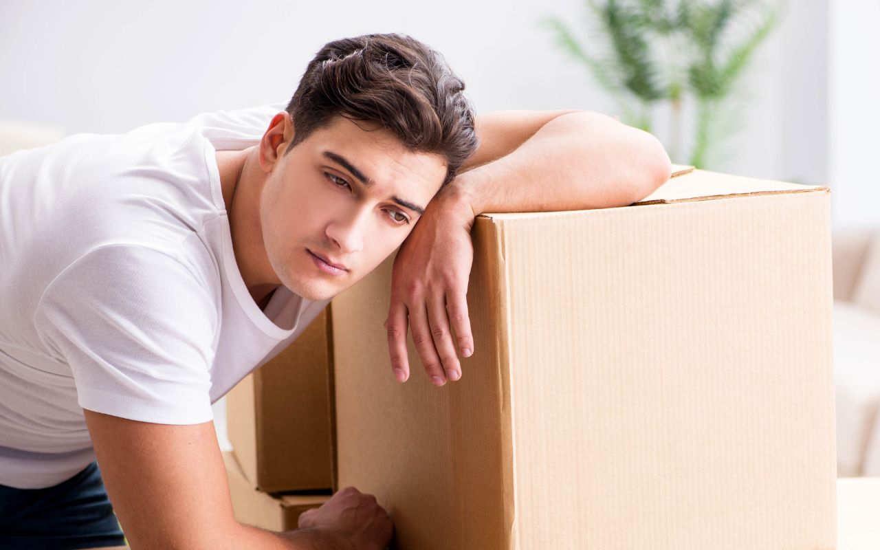 _Man looking tired leaning on a moving box