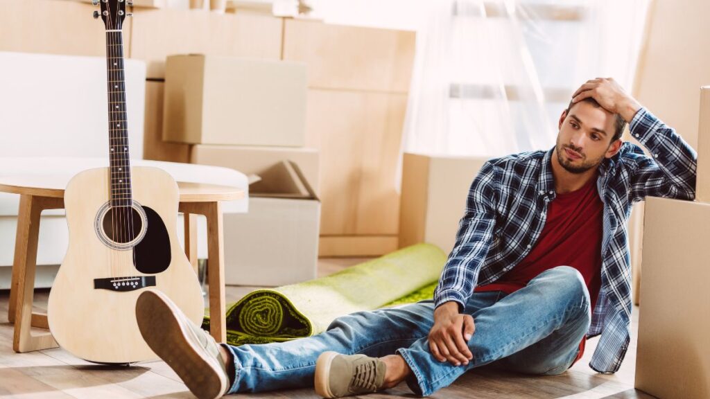 Man on the floor surrounded by moving boxes 