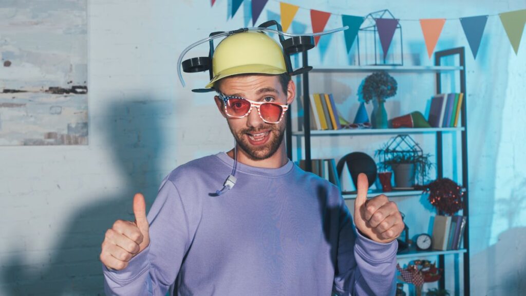 Man ready to party. Wearing a beer drinking hat, crooked sun glasses and giving two thumbs up