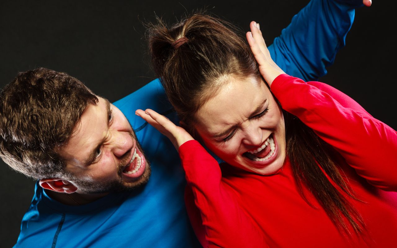 man screaming at a woman and woman covering her ears upset