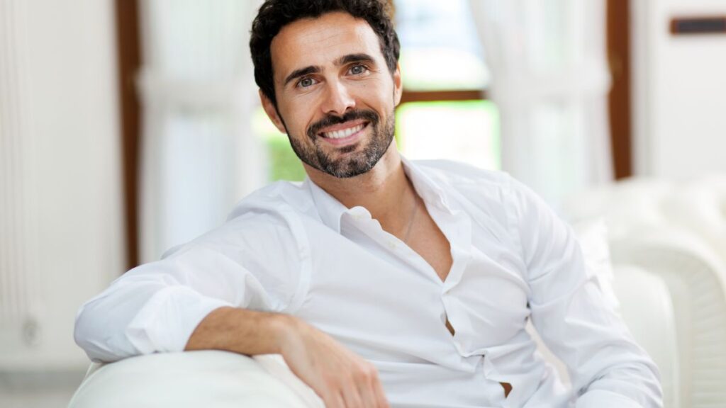 man sitting and smiling on the couch