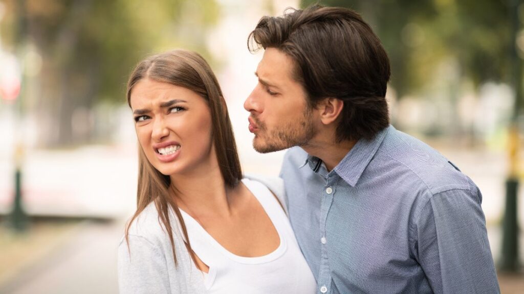 man trying to kiss an unhappy cringing woman