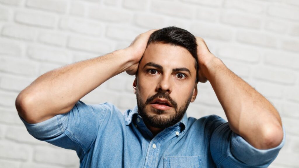 man upset with hands on his head