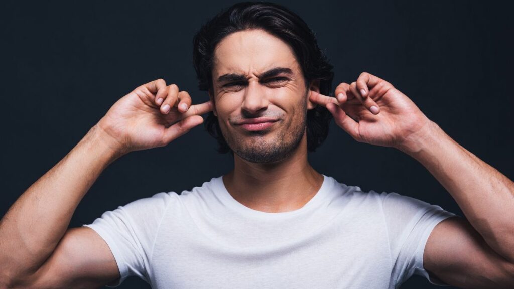 man with his hands in his ears looking annoyed