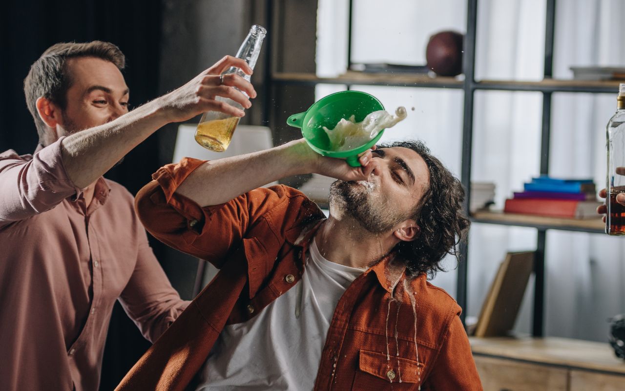 men drinking, one with a funnel