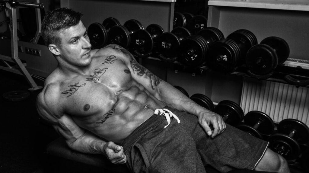 muscular man laying on a gym bench shirtless