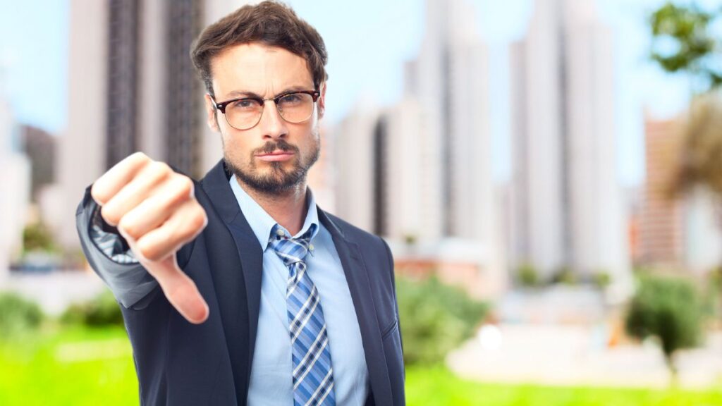 Negativity man standing outside with his hand out and thumb down, making an upset face